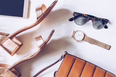 moda blog kavramı beyaz arka plan üzerinde. kadın aksesuarları: Altın Kol saati, orta ayak bileği kayış, deri toka çanta, cep telefonu ve leopar güneş gözlüğü ile topuk sandaletler en az sayıda düz lay