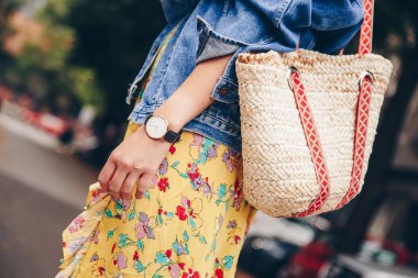 sokak tarzı moda ayrıntılar. trendy beach hasır çanta tutan bir yazlık elbise ve beyaz ve siyah analog kol saati, giyen kadın. mükemmel yaz 2018 moda aksesuarları. 