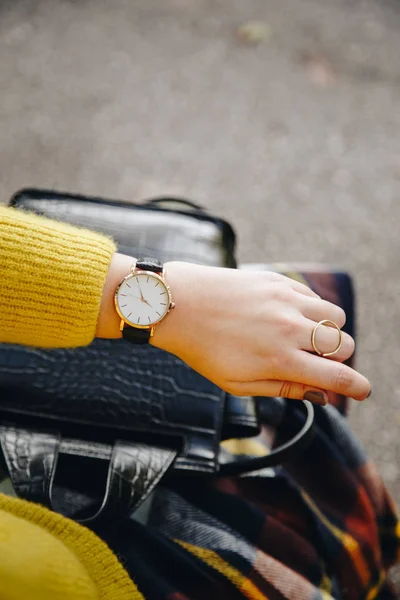 street style fashion details. close up, young fashion blogger wearing a sweater and a analog wrist watch. stylish woman checking the time on her watch. autumn/fall season.