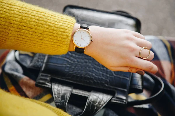 street style fashion details. close up, young fashion blogger wearing a sweater and a analog wrist watch. stylish woman checking the time on her watch. autumn/fall season.