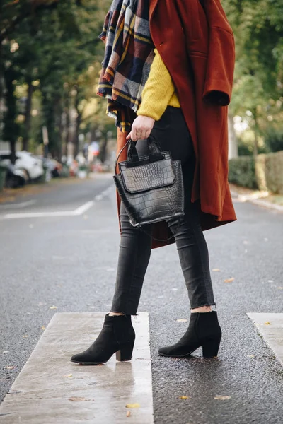 street style, attractive woman wearing a brown oversized coat,black jeans, ankle boots and a croc effect tote bag. fashion outfit perfect for sunny autumn.