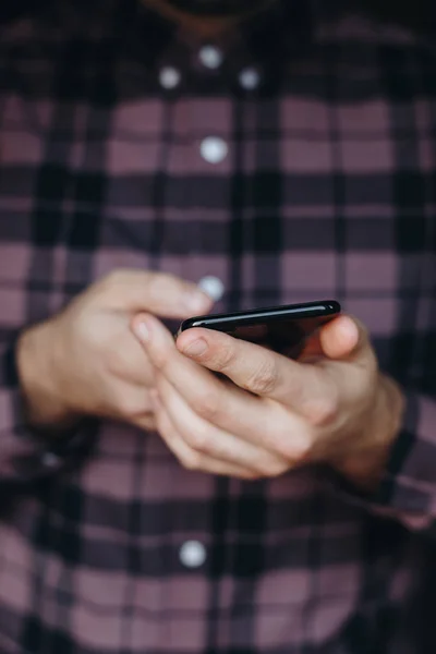 close up of man using smartphone. concept of phone addiction. young business man typing and browsing social media on his phone, texting and social networking, staying connected in a modern world.