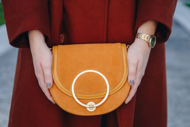 sokak tarzı moda ayrıntılar. genç moda blogger giyen kahverengi kış ceket ve siyah ve altın analog Bilek izlemek kapatın. bir güzel süet deri çanta elinde süre kontrol.