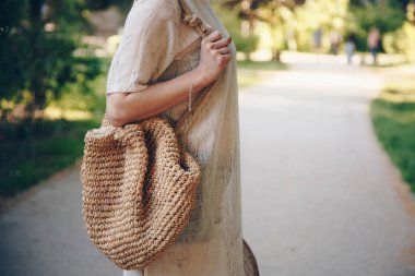 Güneşli bir günde bir hasır şapka ve çanta onun elinde tutan şık bir kadının yakın çekim