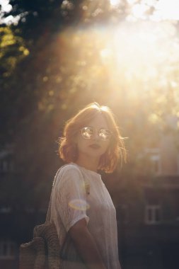 Güneş gözlüğü takıyor ve açık havada bir yaz gününde poz güzel bir kırmızı saçlı kadın portresi sokak stili