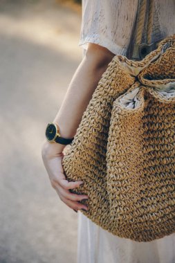 Yazlık elbise giyen ve hasır çanta şık kol saati giyen süre tutan şık bir kadının yakın çekim