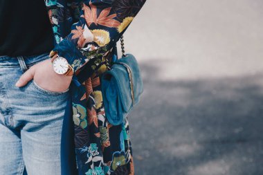street style fashion details. close up, young fashion blogger wearing a floral jacket, and a white and golden analog wrist watch. checking the time, holding a beautiful suede leather purse. clipart