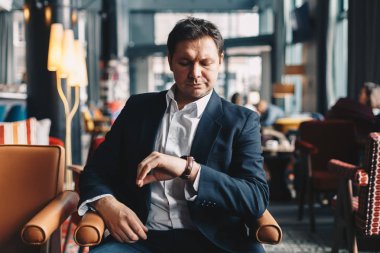 Close-Up zaman kol üzerinde kontrol iş, bir öğle yemeği molası sırasında bir restoranda oturan zarif genç adam. Zaman kavramını paradır.