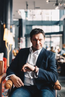 Kafe barda oturmuş, bir iş görüşmem var birine bekliyormuş gibi onun el bakarak iyi görünümlü genç adam. Zaman kavramını paradır. Dikey metin için yer resimle.