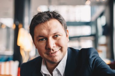 Gülümseyen ve kameraya bakarak iş, bir mola sırasında bir kafe barda bir selfie alma iyi görünümlü genç adam Close-Up.