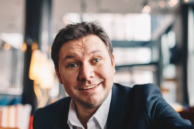 Gülümseyen ve kameraya bakarak iş, bir mola sırasında bir kafe barda bir selfie alma iyi görünümlü genç adam Close-Up.