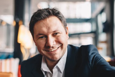 Gülümseyen ve kameraya bakarak iş, bir mola sırasında bir kafe barda bir selfie alma çekici genç adam Close-Up.