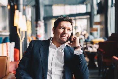 Bir iş yaparken bir restoranda oturan erkek Yöneticisi yakışıklı genç bir smartphone holding ortağı ile ara. Bir ara çalışma kavramı.