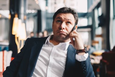 Bir iş ortağı ile bir akıllı telefon tutarak arama yaparken bir restoranda oturan genç iyi görünümlü şirket adam. Bir ara çalışma kavramı.