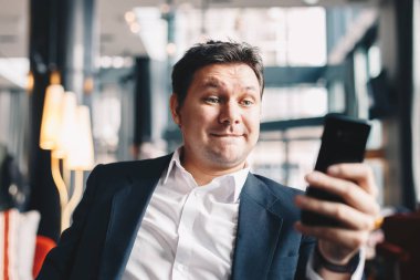 Close-up çekici genç adam süre oturan bir kafe barda iş bir mola sırasında gülümseyen ve cep telefonundan kameraya bakarak video aramasý yapma.