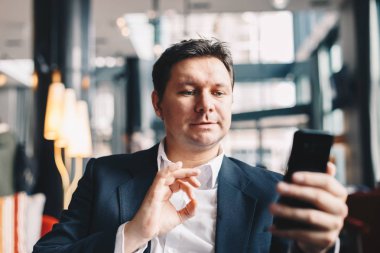 Bir barda oturmuş, mali sermaye yatırımı izlemek için cep telefonunu kullanarak genç çekici erkek broker o yaptı. Borsa takip.