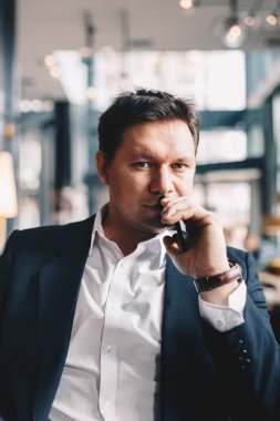 İyi görünümlü genç işadamı ile bir barda oturmuş, kamera için poz yüksek benlik saygısı, yakın çekim portresi. Dikey görüntü metni ve reklam alanı olan.