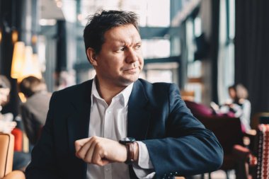 Yakışıklı genç iş adamı biri bir toplantıya geç olduğu için kızgın olman. O bir kafe barda oturmuş ve o zaman onun kol saati üzerinde seyir.