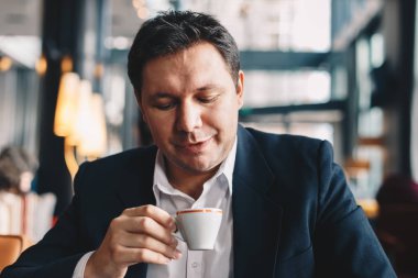 Holding ve iş sonu zevk bir kupa, kahve içme modern bir restoranda oturan genç ve iyi görünümlü avukat.