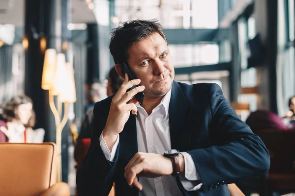 Cep telefonundan konuşuyor ve kol saati, işten bir mola sırasında bir kafe barda oturmuş zaman bakıp onun otuzlu yakışıklı ve kendine güvenen genç işadamı portresi. Para kavramı Zamanı.