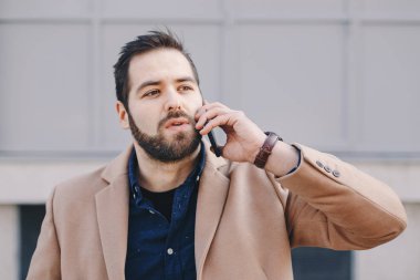 Office dışı bir kesinti sırasında cep telefonundan sohbet çekici ve modern bir genç adam portresi.