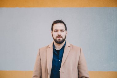 Yakın çekim portre çekici, modern genç adam poz ve çok renkli bir arka plan önünde moda giysiler giyen kameraya bakıyor. Kopyalama, metin ve reklam için yer.