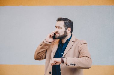 Zaman onun kol saati kontrol cep telefonundan bir kesinti sırasında sohbet bir çekici ve modern genç adam portresi. Metin ve reklam alanı.