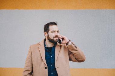 Dışarıda bir modern arka plan önünde poz cep telefonundan bir kesinti sırasında sohbet kalkınan ve modern genç adam portresi. Metin ve reklam alanı.