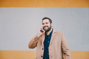 Çok renkli bir arka plan önünde moda giysiler içinde poz cep telefonu sohbet çekici, modern genç adam portresi. Kopyalama, metin ve reklam için yer.