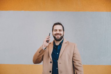 Modern arka plan ouside önünde kamera için poz cep telefonundan bir kesinti sırasında sohbet çekici ve modern genç adam portresi. Metin ve reklam alanı.