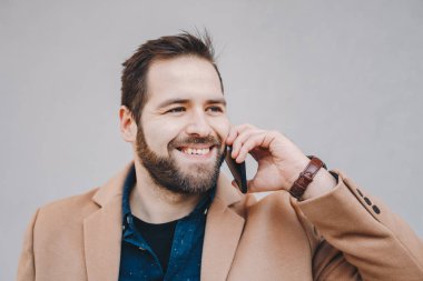 Closeup dışında gri bir arka plan önünde poz cep telefonundan bir kesinti sırasında sohbet bir çekici ve modern genç adam portresi.