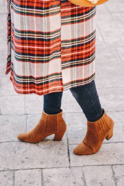 Moda blogger kıyafet ayrıntılar. Ekoseli bir mont, siyah kot pantolon ve deve ayak bileği ayakkabı giyen moda kadın. Detay mükemmel sonbahar ya da Kış moda kıyafet. Dikey görüntü.