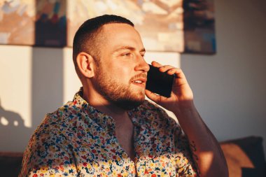 Evde akıllı telefonda konuşurken mutlu yakışıklı adam