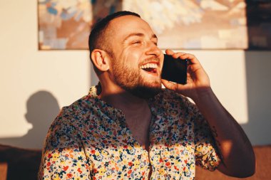 Akıllı telefon üzerinden bir arkadaşıyla bir görüşme sırasında gülen yakışıklı adam