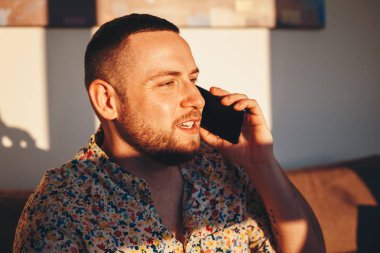 Evde akıllı telefonda konuşurken mutlu yakışıklı adam