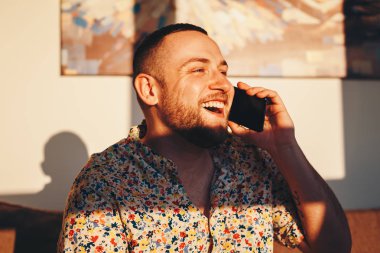 Evde akıllı telefonda konuşurken mutlu yakışıklı adam