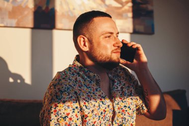 Evde akıllı telefonda konuşurken mutlu yakışıklı adam