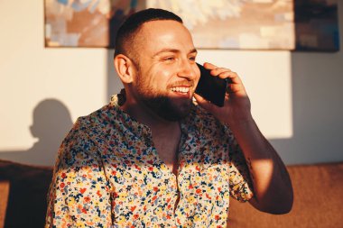 Akıllı telefon üzerinden bir arkadaşıyla bir görüşme sırasında gülen yakışıklı adam