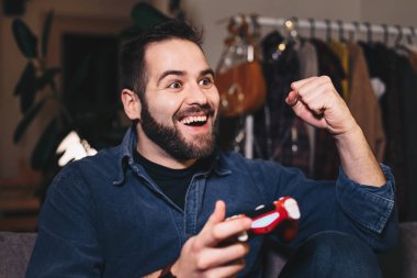 Oturma odasını, mutlu bir video oyunu oynarken o kazanıyor çünkü genç bir adam portresi