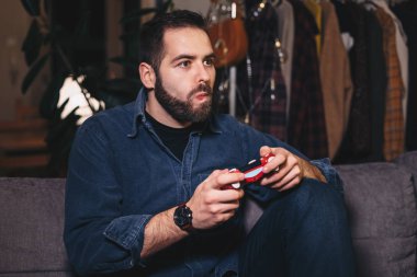 Oturma odasında kanepede onun koltuk kenarına olmak video odaklı üzerinde ilerleme, oyun, genç bir adam portresi.