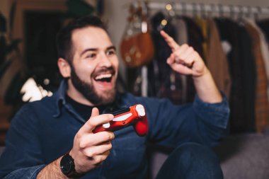 Oturma odasını, mutlu bir video oyunu oynarken o kazanıyor çünkü genç bir adam portresi. Oyun çubuğu üzerinde odaklanmak.