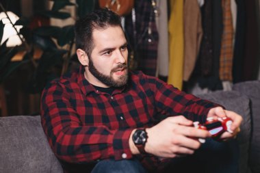 Oturma odasında kanepede koltuğunu kenarında olmanın sonucu hakkında vurguladı video oyunları oynamak genç bir adam portresi.