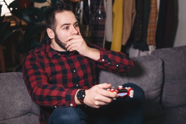 Oturma odasında kanepede onun koltuk kenarına olmak video oyun, genç bir adam portresi.