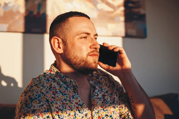 Evde akıllı telefonda konuşurken mutlu yakışıklı adam