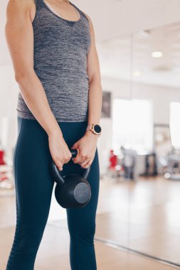 Spor salonunda su ısıtıcısı zilini kaldırarak egzersiz yapmakta olan, spor saati takan, aktif, spor ve sağlıklı yaşam kavramı.