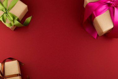 El işi kağıdında üç hediye kutusu ve kırmızı arka planda fotokopi alanı olan renkli kurdelelerle bağlanmış..