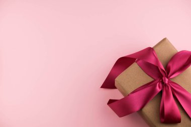 El işi kağıdına sarılı pembe bir kurdeleyle bağlanmış bir hediye kutusu. Boşluğu kopyala.