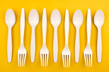 Çevresel fast food kavramı. Çatallar ve kaşıklar dolusu çevre dostu malzeme, sarı arka planda, fotokopi alanı olan yakın plan.