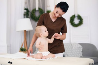 Profesyonel bayan masöz, küçük bir bebek için bir masaj yapar. Modern bir rahat oda içinde kanepede Çocuk Masaj.