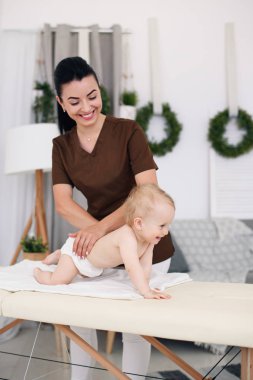 Profesyonel bayan masöz, küçük bir bebek için bir masaj yapar. Modern bir rahat oda içinde kanepede Çocuk Masaj.